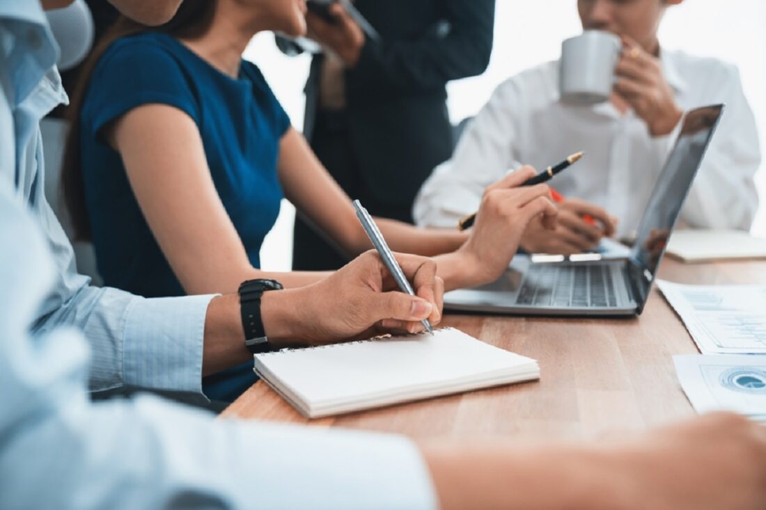 Secretary,Taking,Notes,On,Notebook,At,Corporate,Meeting,With,Group