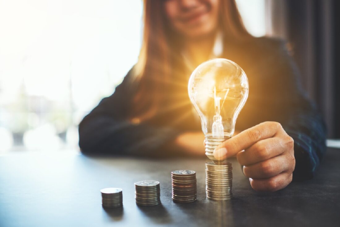 Businesswoman,Holding,And,Putting,Lightbulb,On,Coins,Stack,On,Table