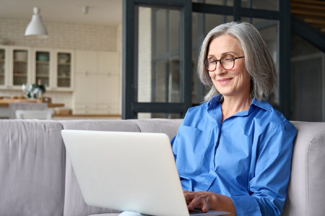 Older,Smiling,60s,Woman,Sitting,At,Home,On,Sofa,,Holding