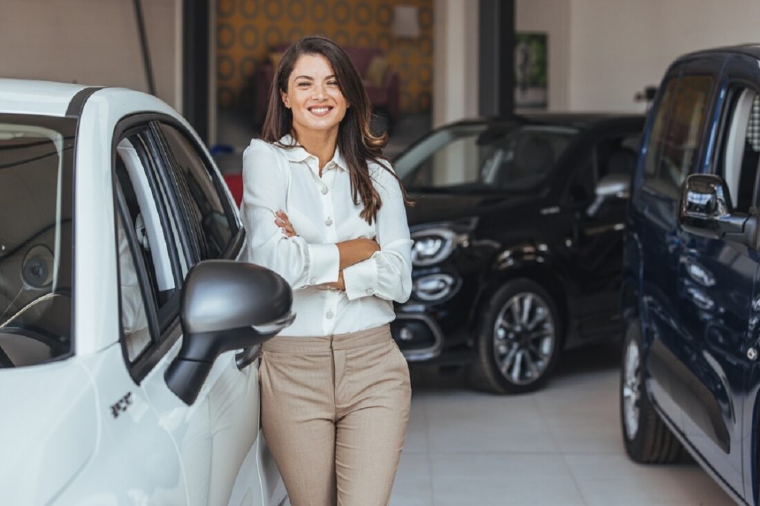 Smiling,Saleswoman,Looking,At,Camera,At,New,Car,Showroom.,Professional