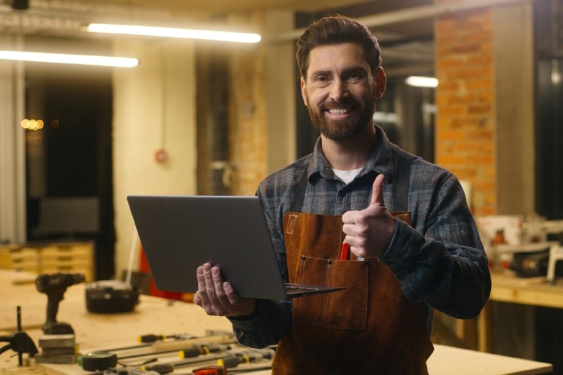 Cheerful,Caucasian,Man,Carpenter,Typing,Laptop,Showing,Thumb,Up,Sign