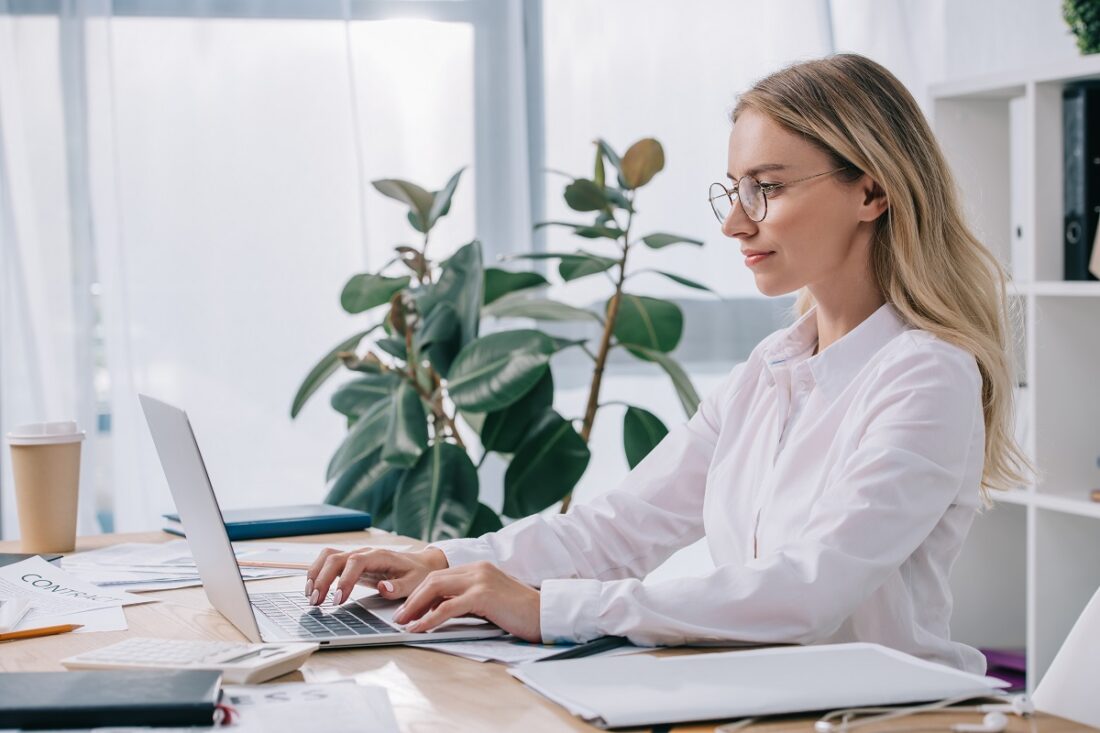 Side,View,Of,Businesswoman,In,Eyeglasses,Working,On,Laptop,At