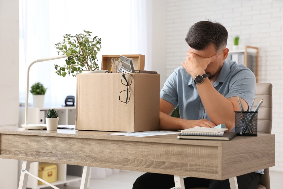 Sad,Fired,Man,With,Box,Of,Personal,Stuff,Sitting,At