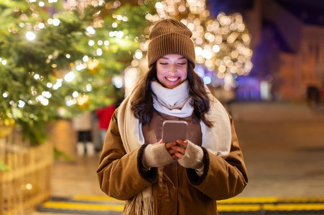 European,Lady,Using,Smartphone,Walking,On,Christmas,Market,,Standing,In